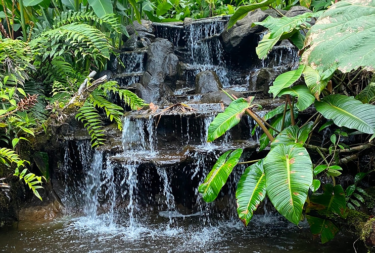 Tranquil waterfall surrounded by lush tropical greenery, showcasing the peaceful lifestyle accessible with Costa Rica home loans.